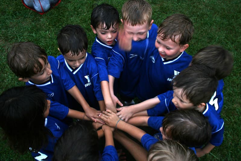a team of children at sports practice doing a pre-match huddle